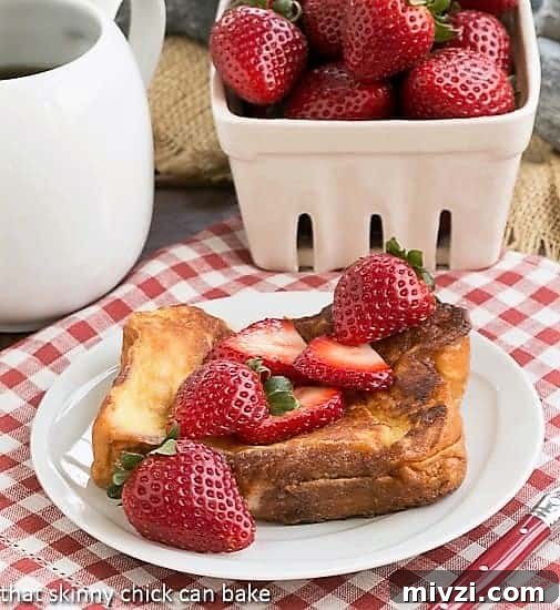 Strawberry Mascarpone Stuffed French Toast - An elegant brunch entree! Strawberry Mascarpone Stuffed French Toast on a white plate topped with fresh strawberries.