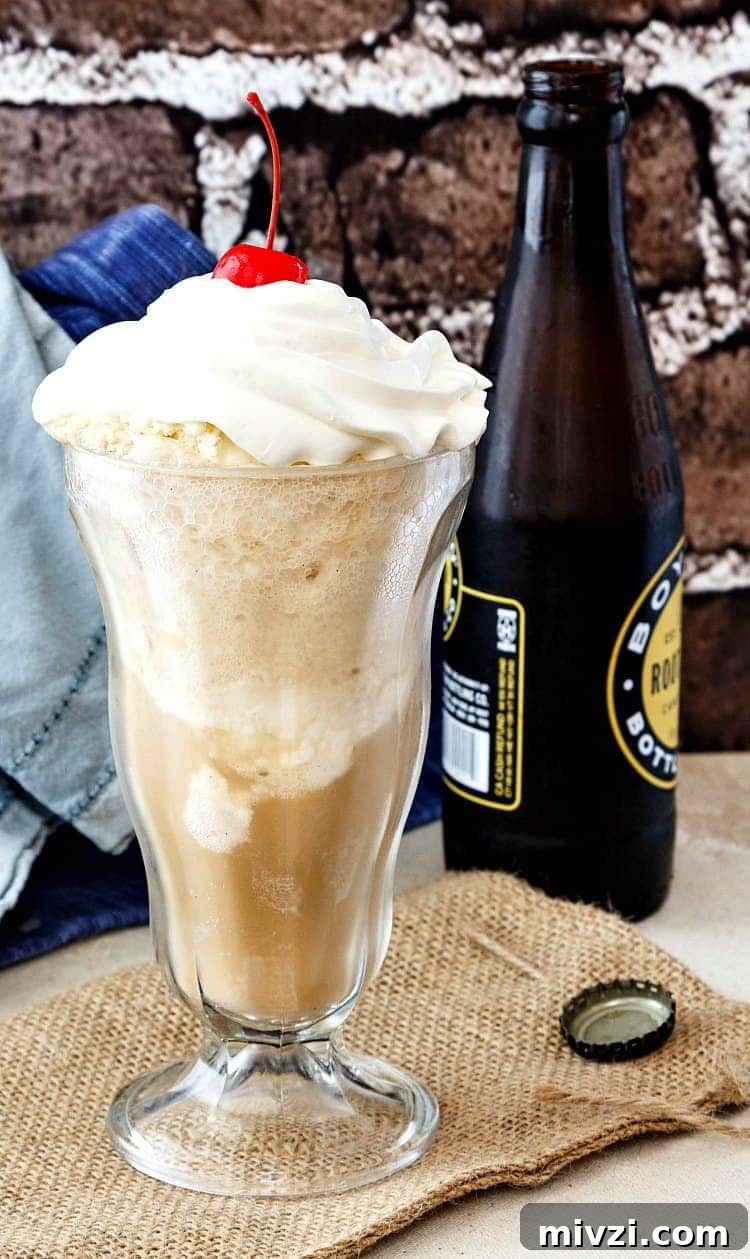 A tall glass of root beer float with a cherry on top and a bottle of root beer next to it.