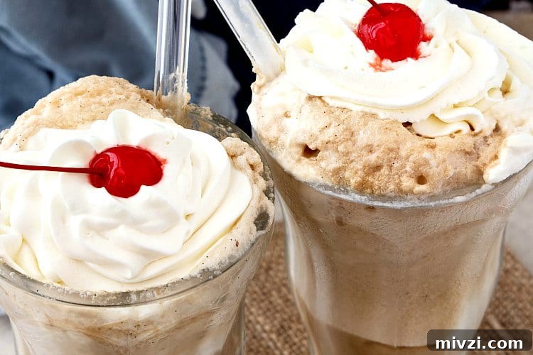 Two root beer floats with whipped cream and cherries on top.