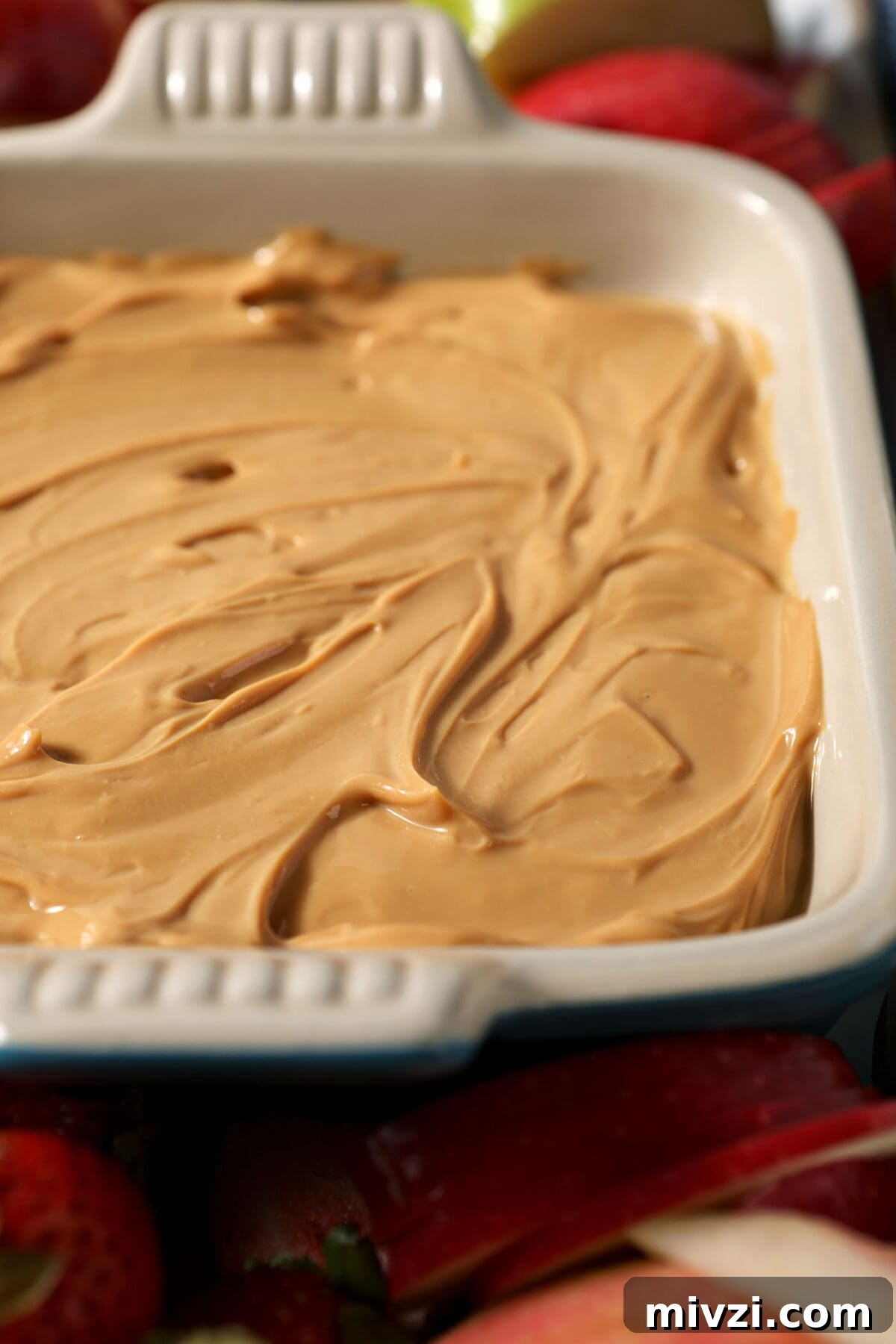Creamy Dulce de Leche Dip Recipe for Desserts and Snacks 7 Side angle of caramel dulce de leche dip in a serving dish surrounded by apples