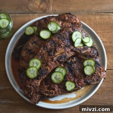 Grilled beef short ribs on a white plate topped with quick pickles.