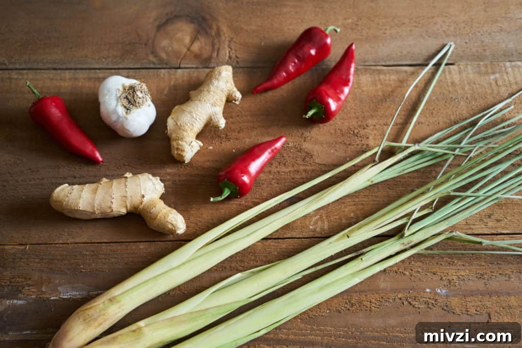 Lemongrass, fresno chiles, garlic, and ginger on a wooden surface.