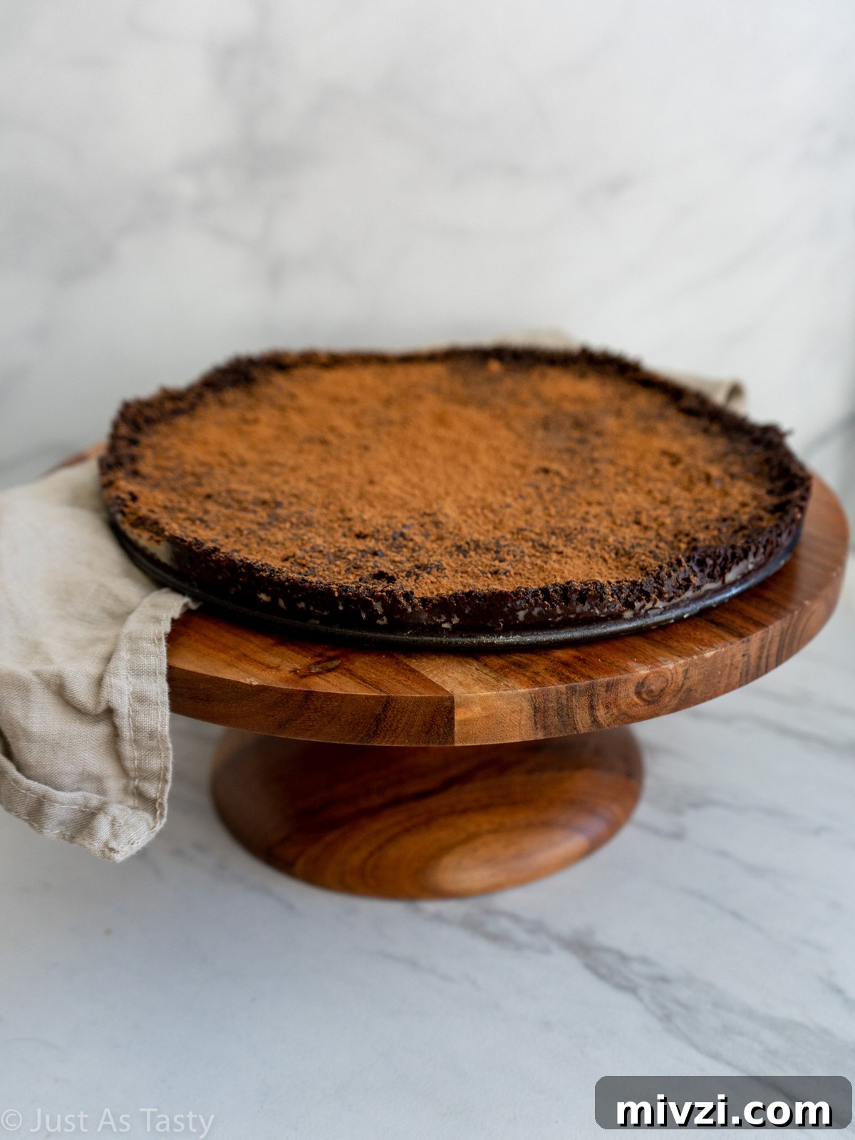 Decadent Flourless Chocolate Cake — Gluten-Free & Eggless 2 Flourless chocolate cake dusted with cocoa powder on a brown cake stand.