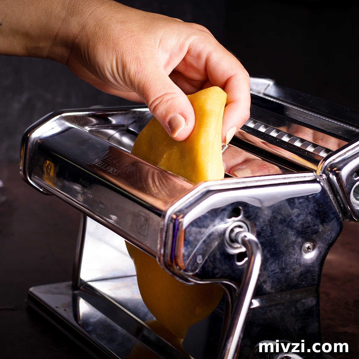 Homemade Pappardelle Recipe: Fresh Pasta from Scratch 13 Feeding dough into a pasta machine on it's widest setting.