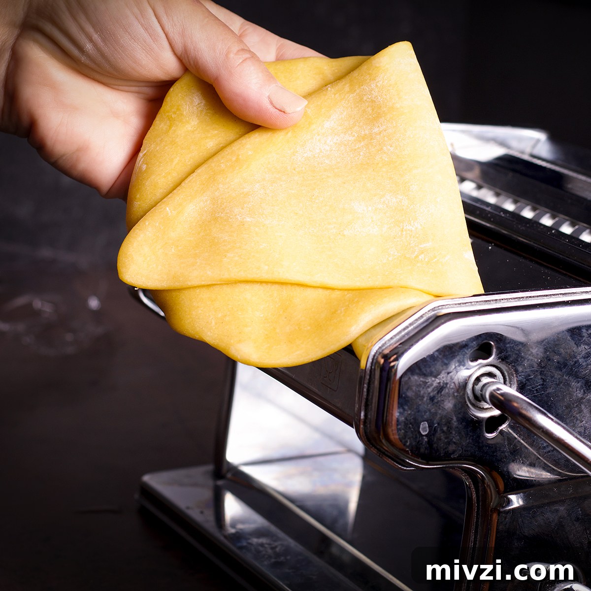 Homemade Pappardelle Recipe: Fresh Pasta from Scratch 14 Folding a piece of pasta dough in half before feeding it back through the rollers of a pasta machine.