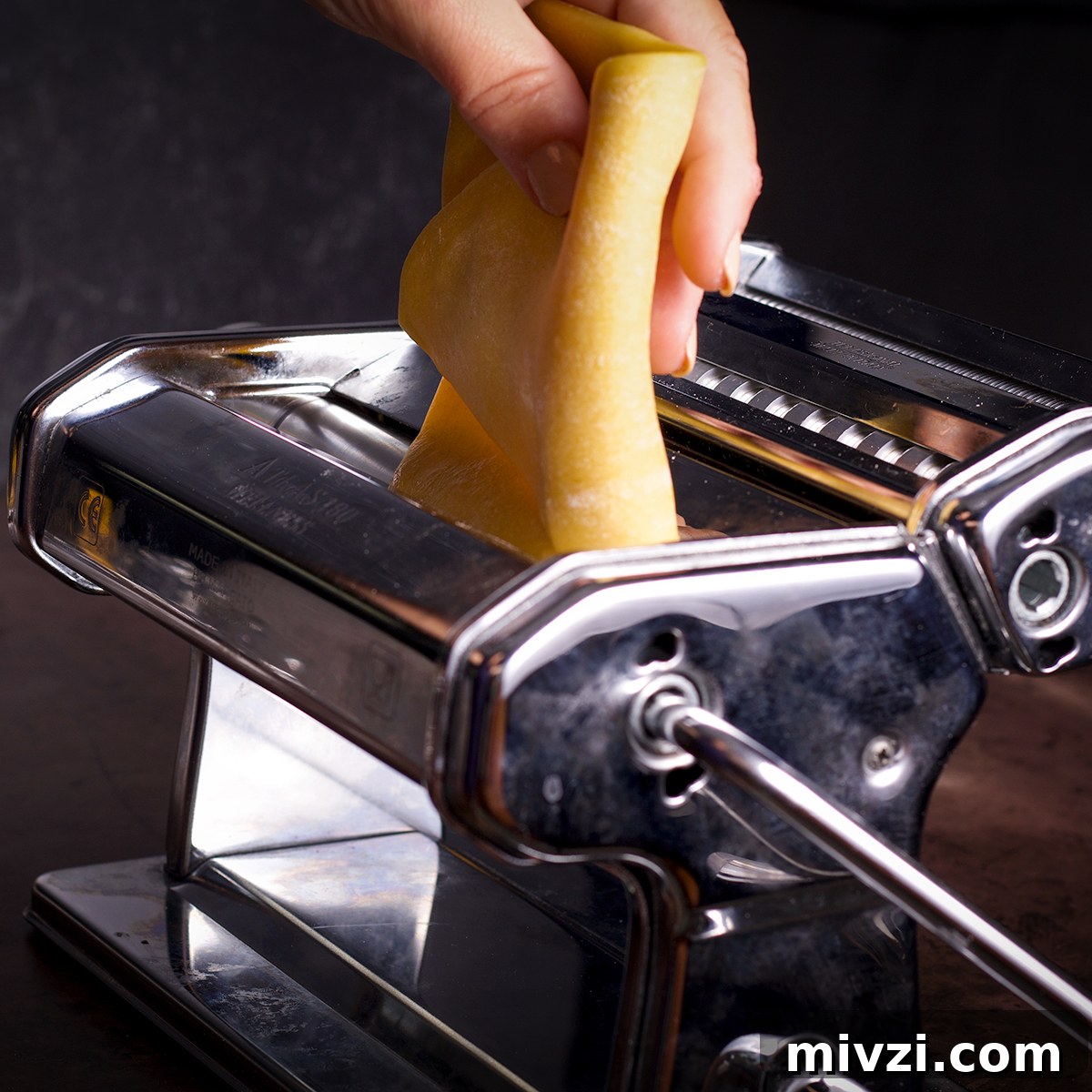 Homemade Pappardelle Recipe: Fresh Pasta from Scratch 15 Rolling a piece of pasta dough through the rollers of a pasta maker.