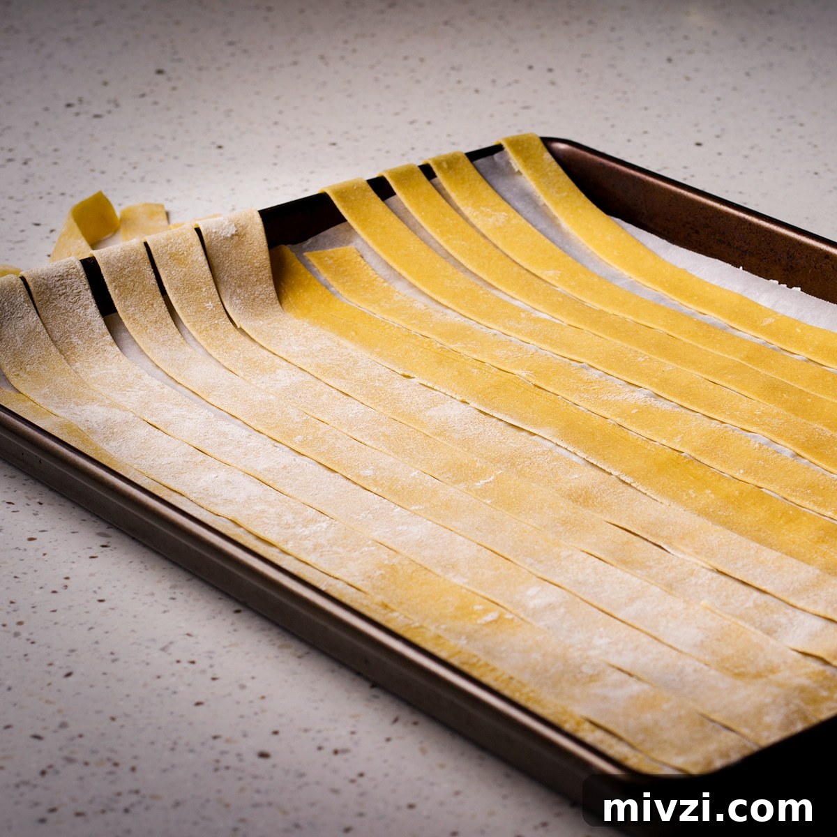 Homemade Pappardelle Recipe: Fresh Pasta from Scratch 19 Homemade pappardelle noodles laid out across a parchment paper lined baking sheet.
