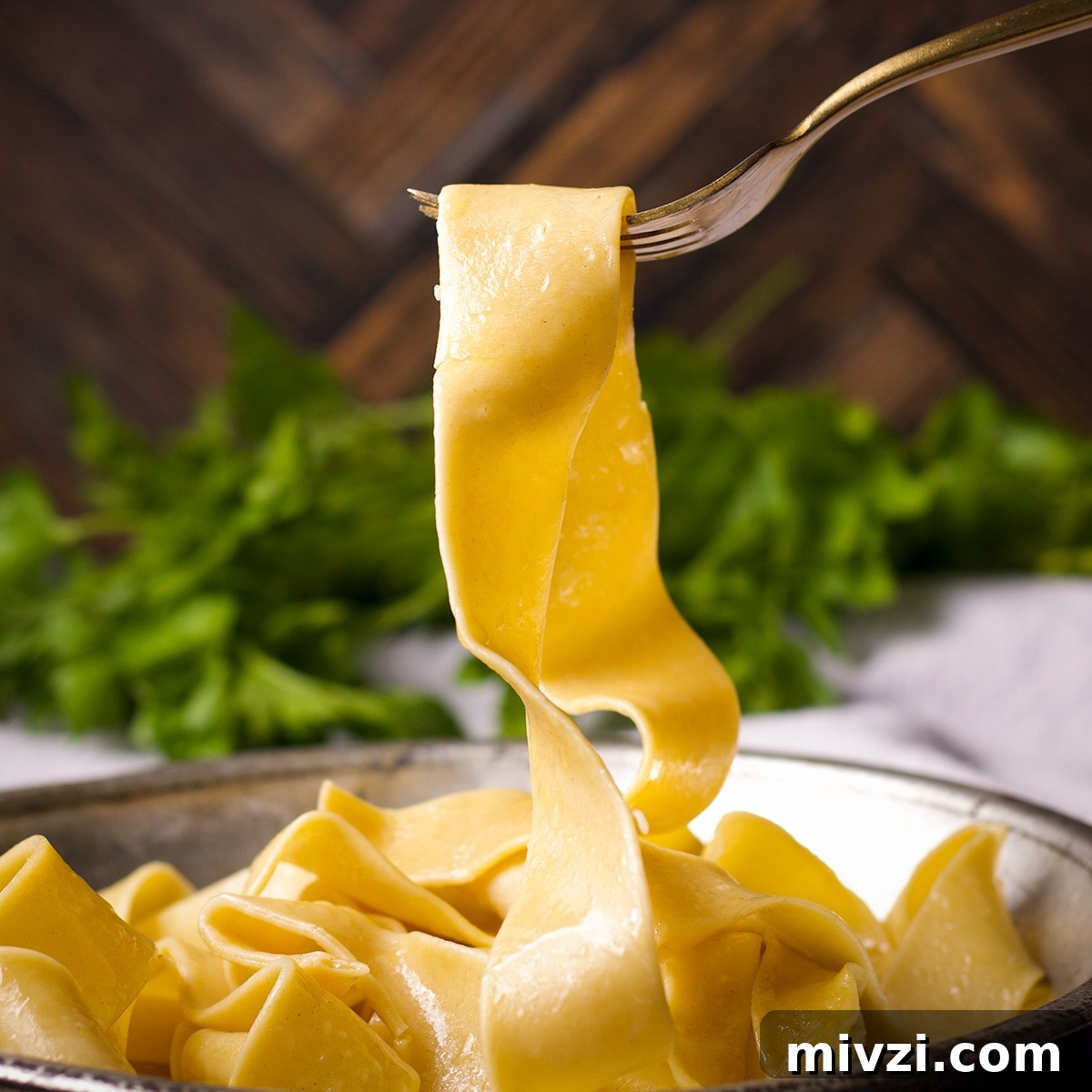 Homemade Pappardelle Recipe: Fresh Pasta from Scratch 22 Someone using a fork to lift a cooked pappardelle noodle from a tin plate.