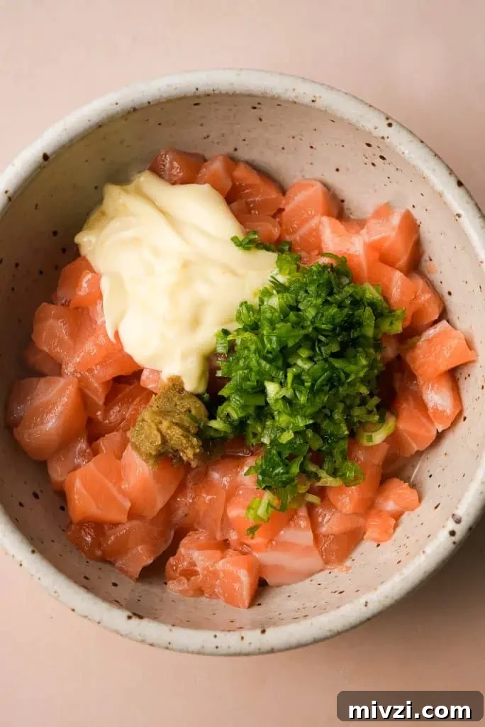 sushi-grade salmon topped with seasoning ingredients, prior to mixing