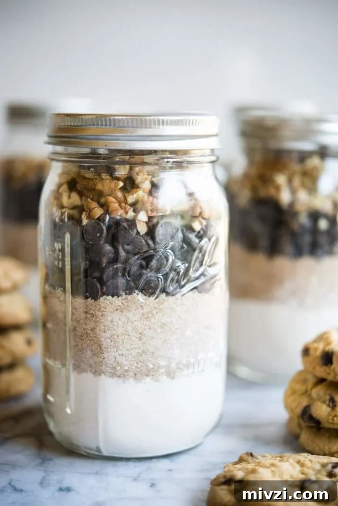 Gluten-Free Chocolate Chip Cookie Mix — Homemade Taste, Ready to Bake 3 Gluten free chocolate chip cookie mix in mason jars on a marble slab surrounded by chocolate chip cookies