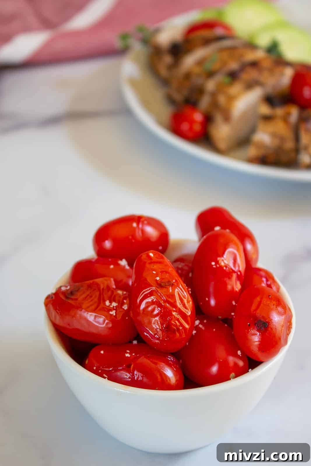 Oven-Roasted Cherry Tomatoes with Garlic and Herbs 8 Grilled tomatoes in a small white bowl.