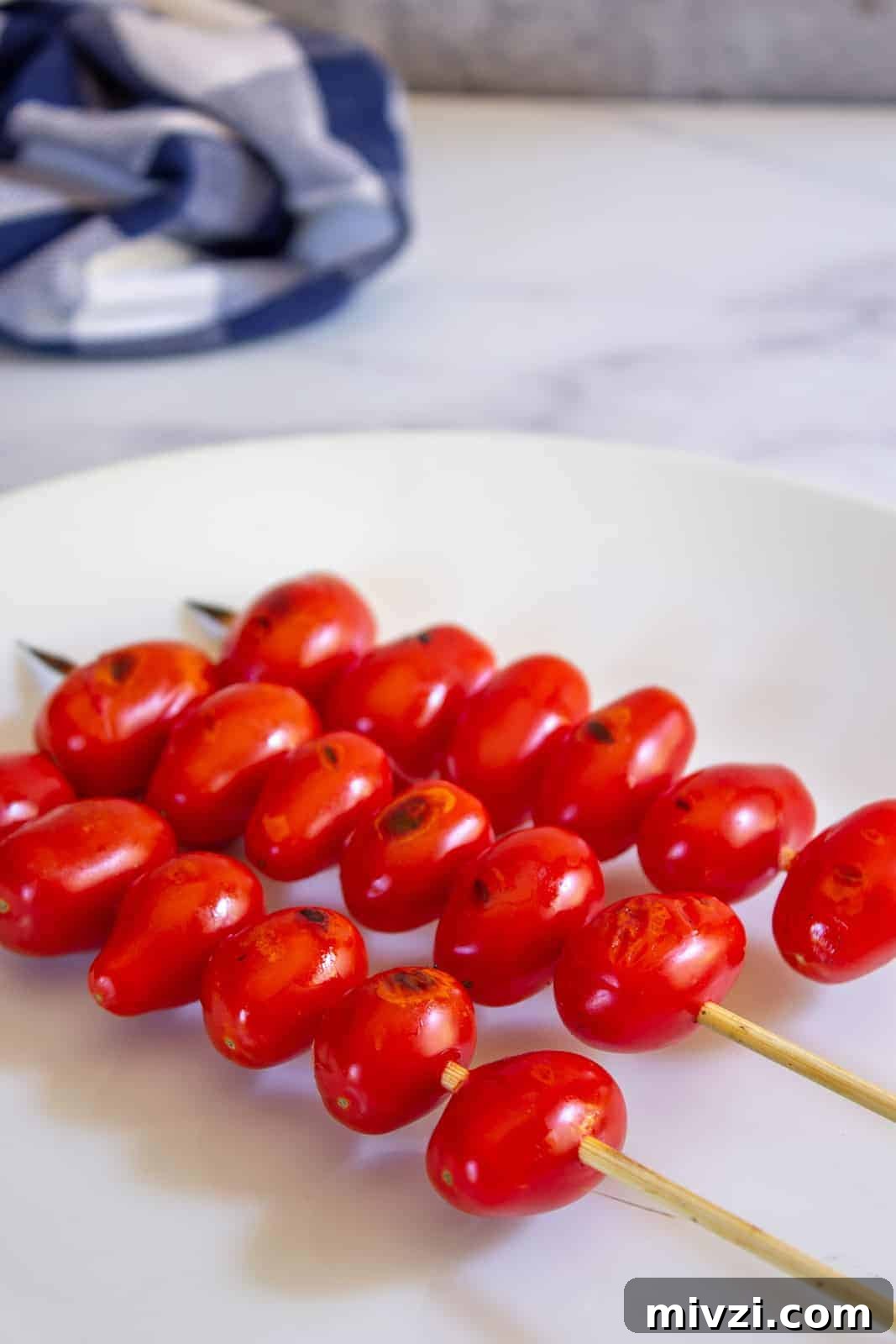 Oven-Roasted Cherry Tomatoes with Garlic and Herbs 9 Cherry tomatoes on a wooden skewer.