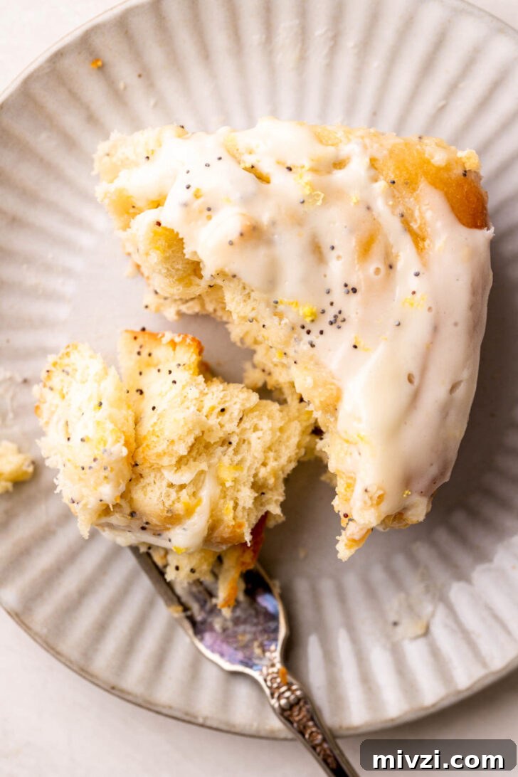 Bite missing from lemon roll on a plate.