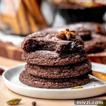 Chocolate chai cookies stacked on a plate. The top cookie has a bite removed.