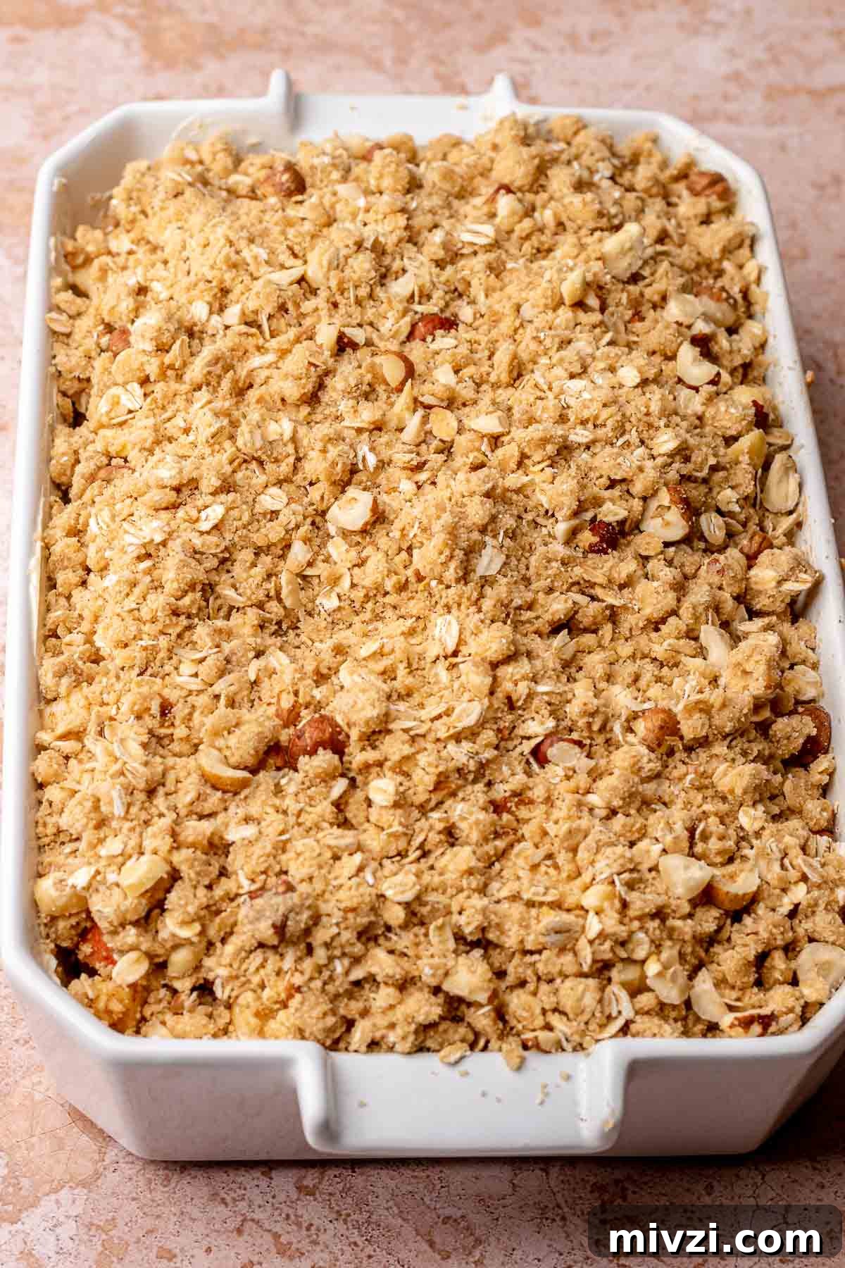 Toffee crumble on top of apples in a baking dish.