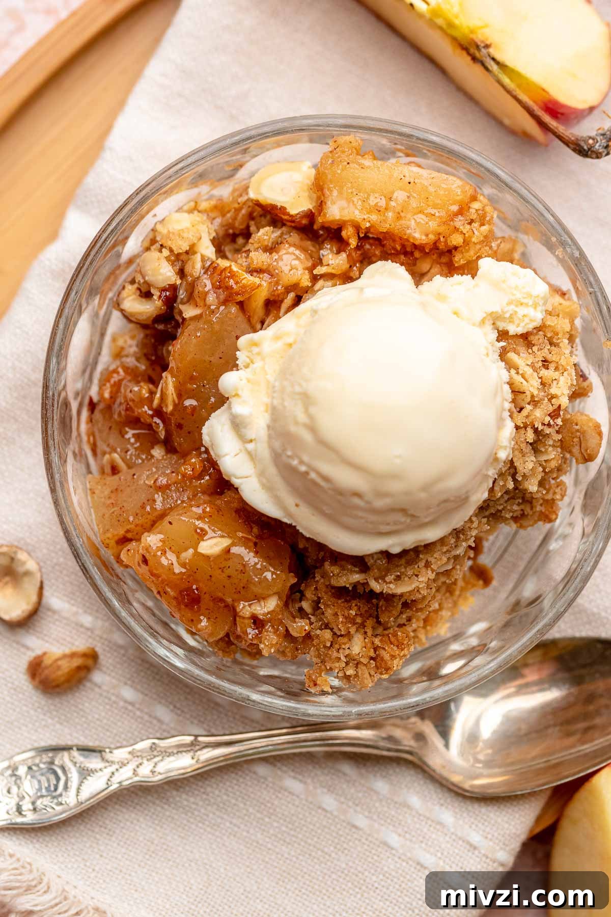 Toffee apple hazelnut crumble in a bowl with ice cream on top.