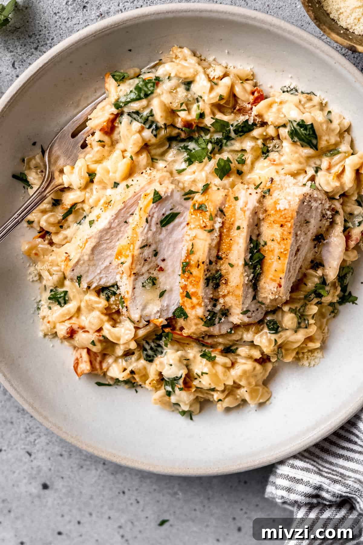 Tuscan chicken orzo in a white bowl on a blue table.