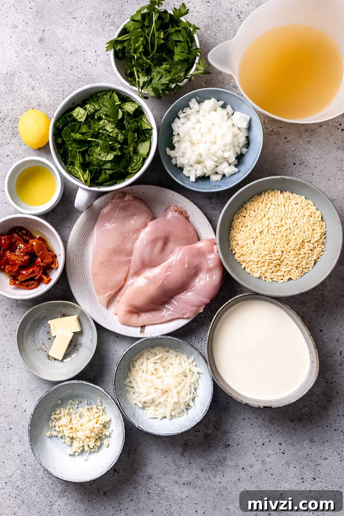 Ingredients for Tuscan chicken and orzo on a blue table.