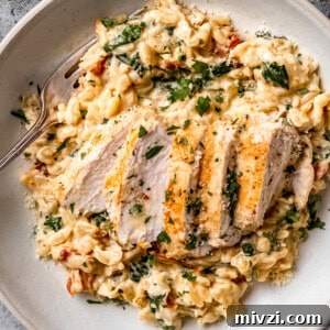 Tuscan chicken orzo in a white bowl on a blue table.