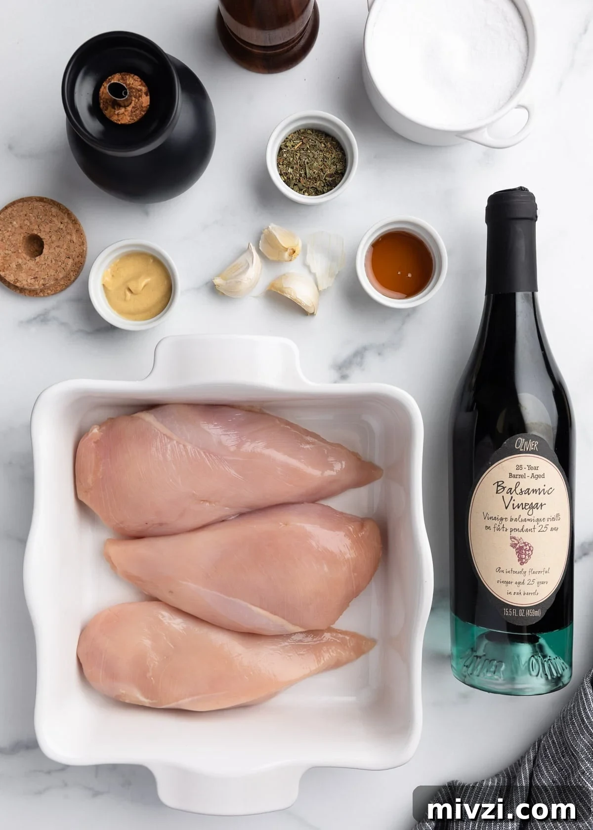 Balsamic-Marinated Chicken Breasts for Juicy Weeknight Meals 3 overhead photo of boneless skinless chicken breasts in a white baking dish, surrounded by a bottle of balsamic vinegar and marinade ingredients in small bowls