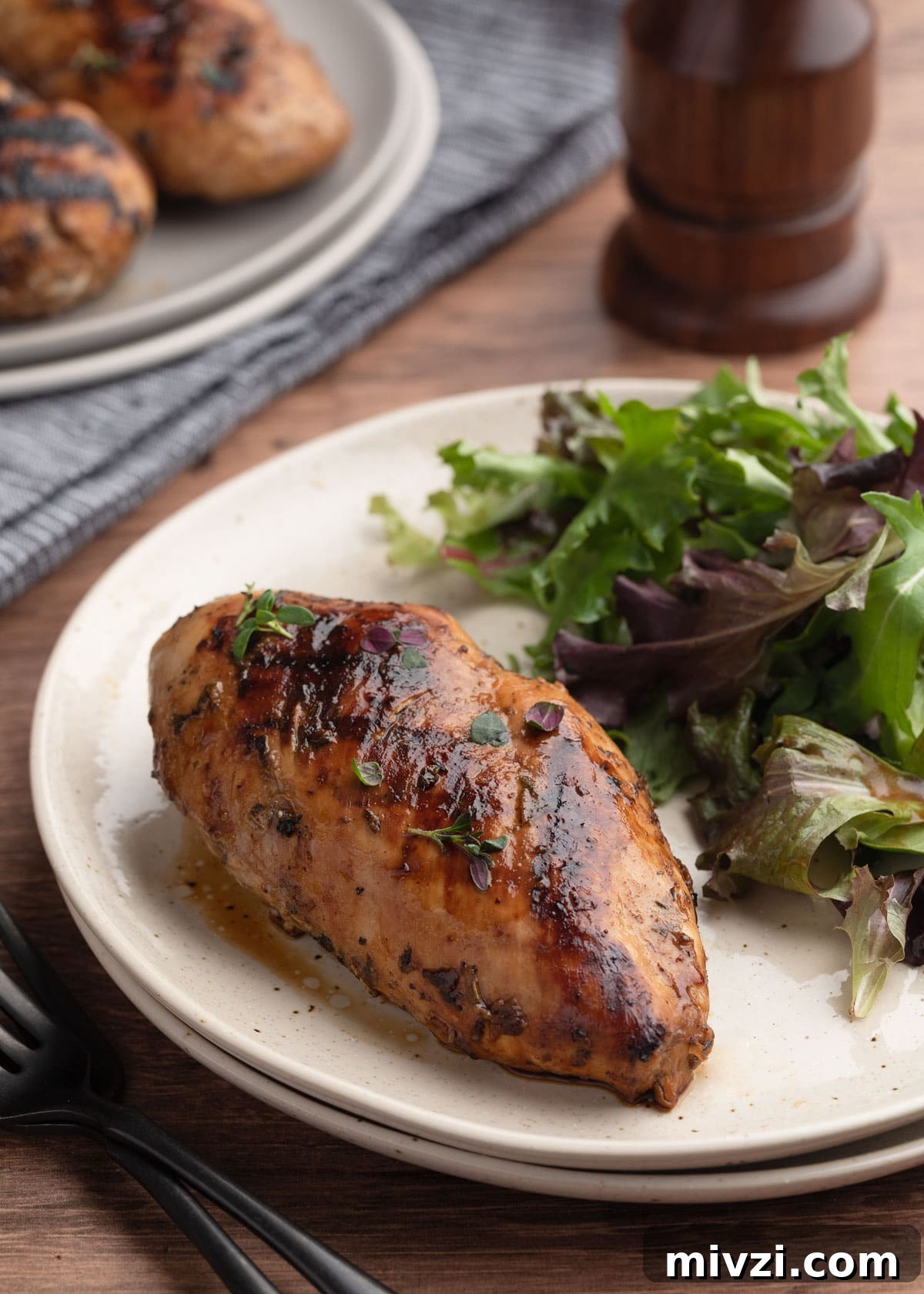 Balsamic-Marinated Chicken Breasts for Juicy Weeknight Meals 8 whole grilled balsamic chicken breast on an ivory plate with spring greens