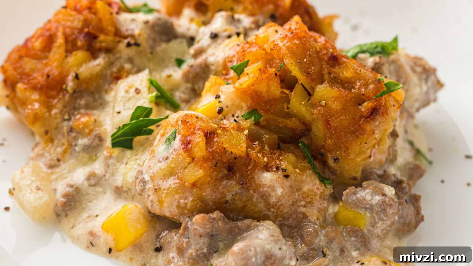 35 Comforting Casserole Recipes to Rely on Tonight 15 A close-up of a casserole dish featuring tater tots, creamy sauce, ground beef, corn, and garnished with chopped parsley.