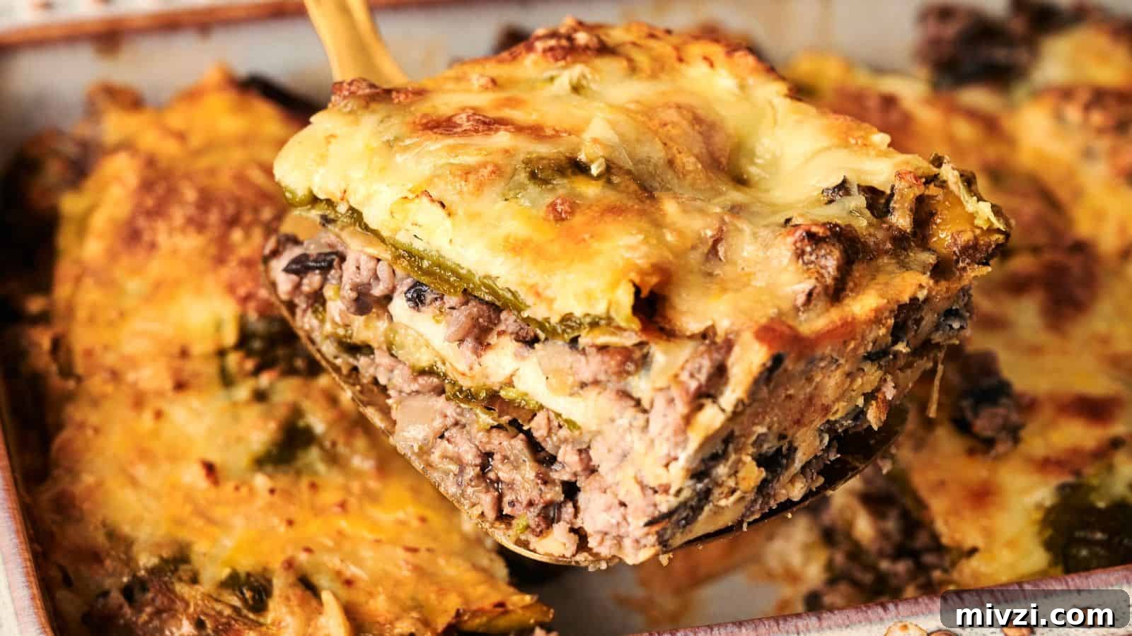 35 Comforting Casserole Recipes to Rely on Tonight 16 A slice of lasagna with beef, mushrooms, cheese, and vegetables being lifted from a baking dish.