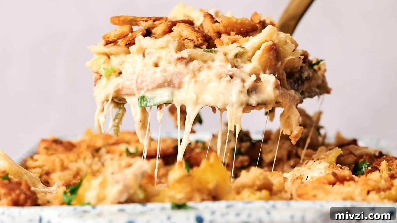 35 Comforting Casserole Recipes to Rely on Tonight 19 A serving spoon lifts a portion of creamy, baked casserole with a crunchy topping, revealing melted cheese.
