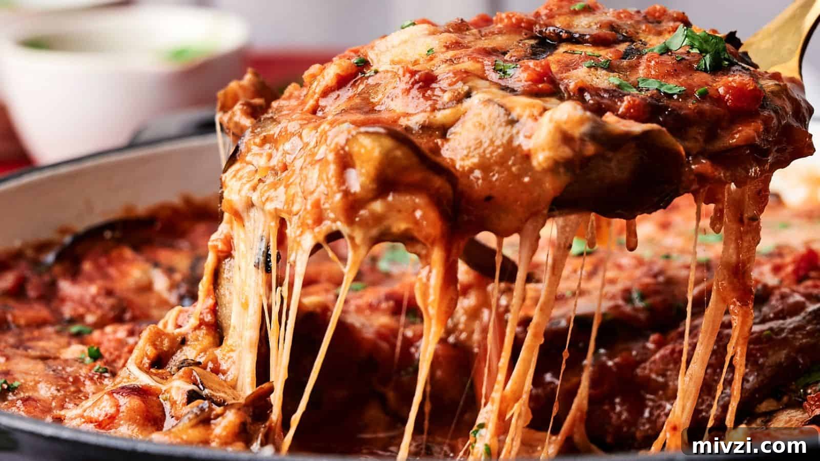 35 Comforting Casserole Recipes to Rely on Tonight 33 A slice of cheesy eggplant lasagna with tomato sauce is being lifted from a pan, showing stretchy melted cheese. A bowl is blurred in the background.