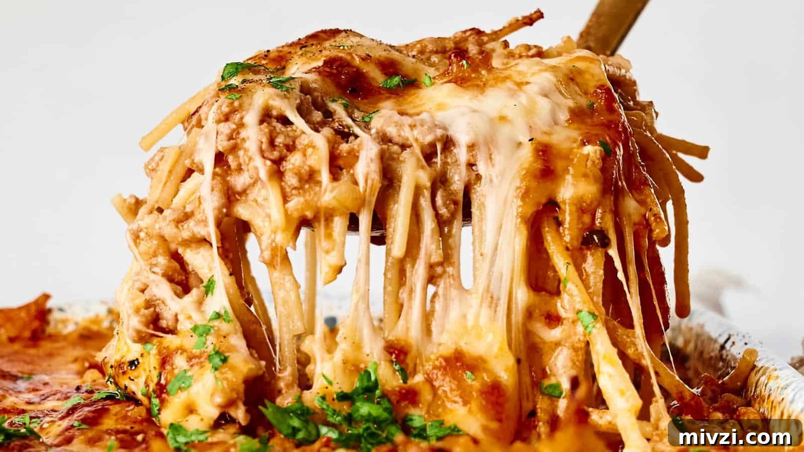 35 Comforting Casserole Recipes to Rely on Tonight 34 A serving of cheesy baked spaghetti is being lifted with a utensil. The dish is topped with melted cheese and garnished with herbs.