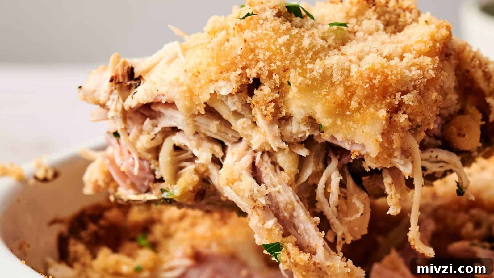 35 Comforting Casserole Recipes to Rely on Tonight 36 Close-up of a serving of chicken cordon bleu casserole with shredded chicken, ham, melted cheese, and breadcrumb topping, garnished with parsley.