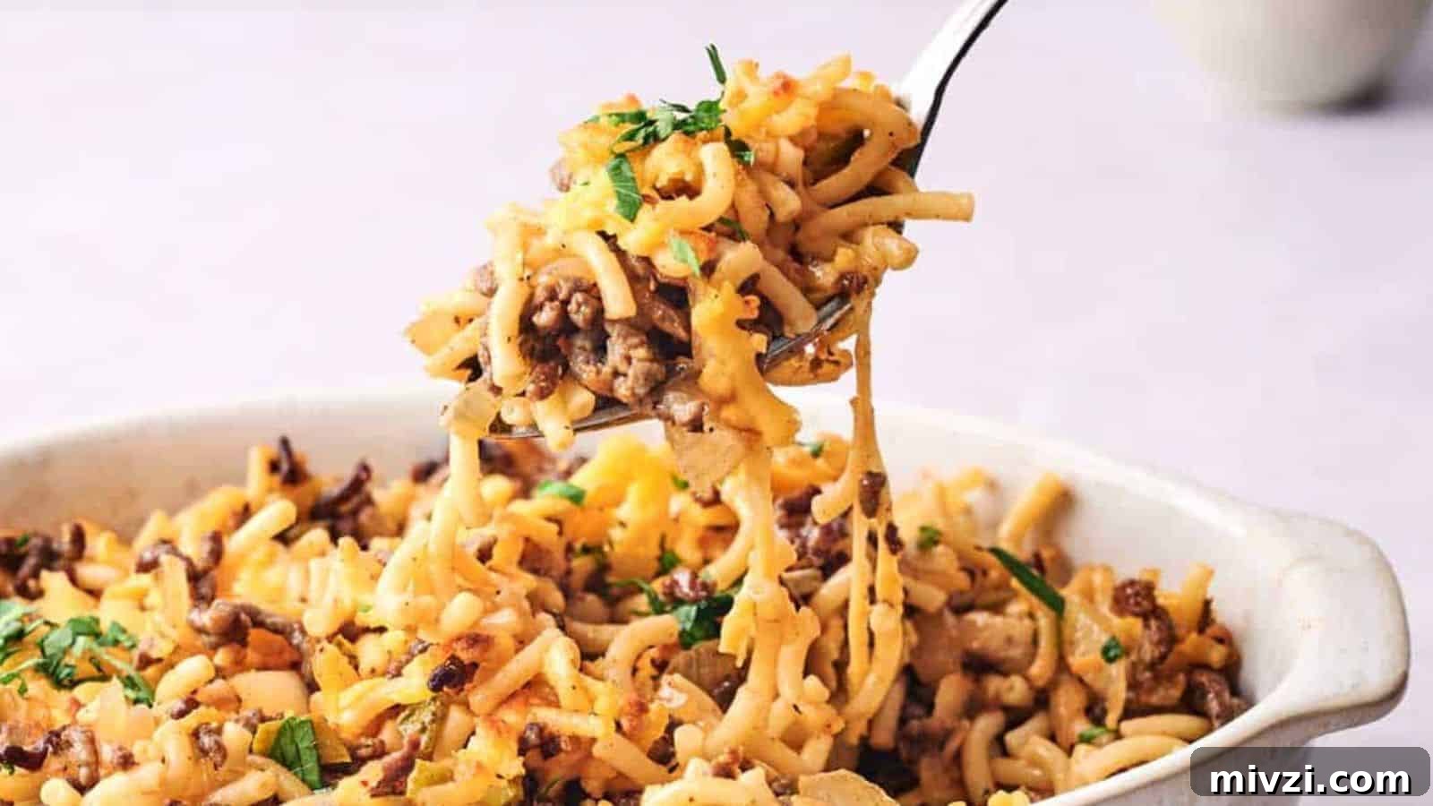 35 Comforting Casserole Recipes to Rely on Tonight 6 Fork lifting a serving of cheesy cheeseburger casserole garnished with parsley.