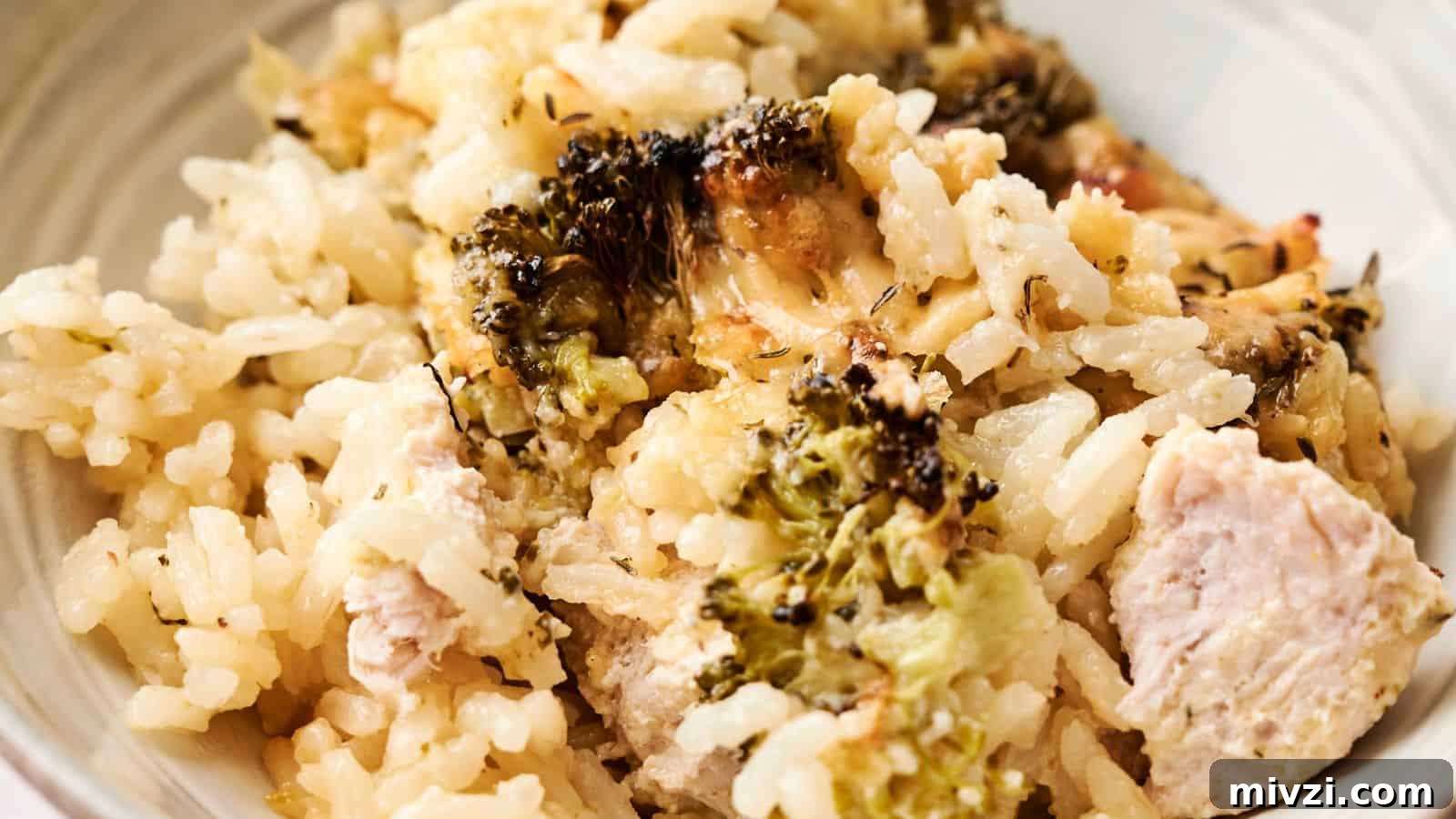 35 Comforting Casserole Recipes to Rely on Tonight 8 A close-up of a chicken and broccoli casserole featuring browned cheese, herbs, and green leafy garnish on top, displayed in a rectangular baking dish.