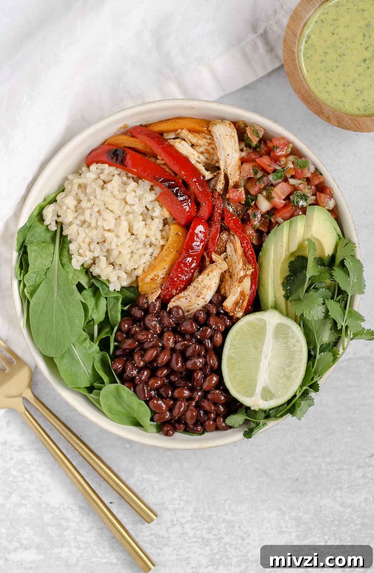 chicken fajita salad in a white salad bowl with a bowl of cilantro dressing off to the side