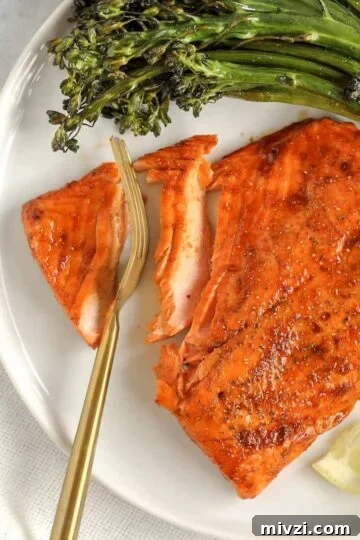 A gold fork cutting into a salmon fillet.
