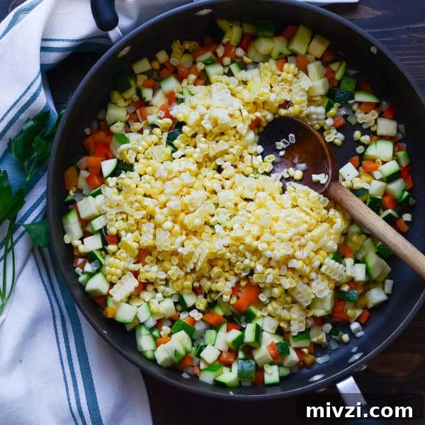 Confetti Corn: Colorful Baked Corn Recipe with Rainbow Veggies 6 chopped vegetables in a pan with wooden spoon.