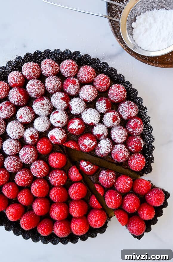 Romantic Valentine’s Day Dessert Ideas and Recipes 15 Top-down view of Easy No-Bake Chocolate Tart with Raspberries half dusted with powdered sugar