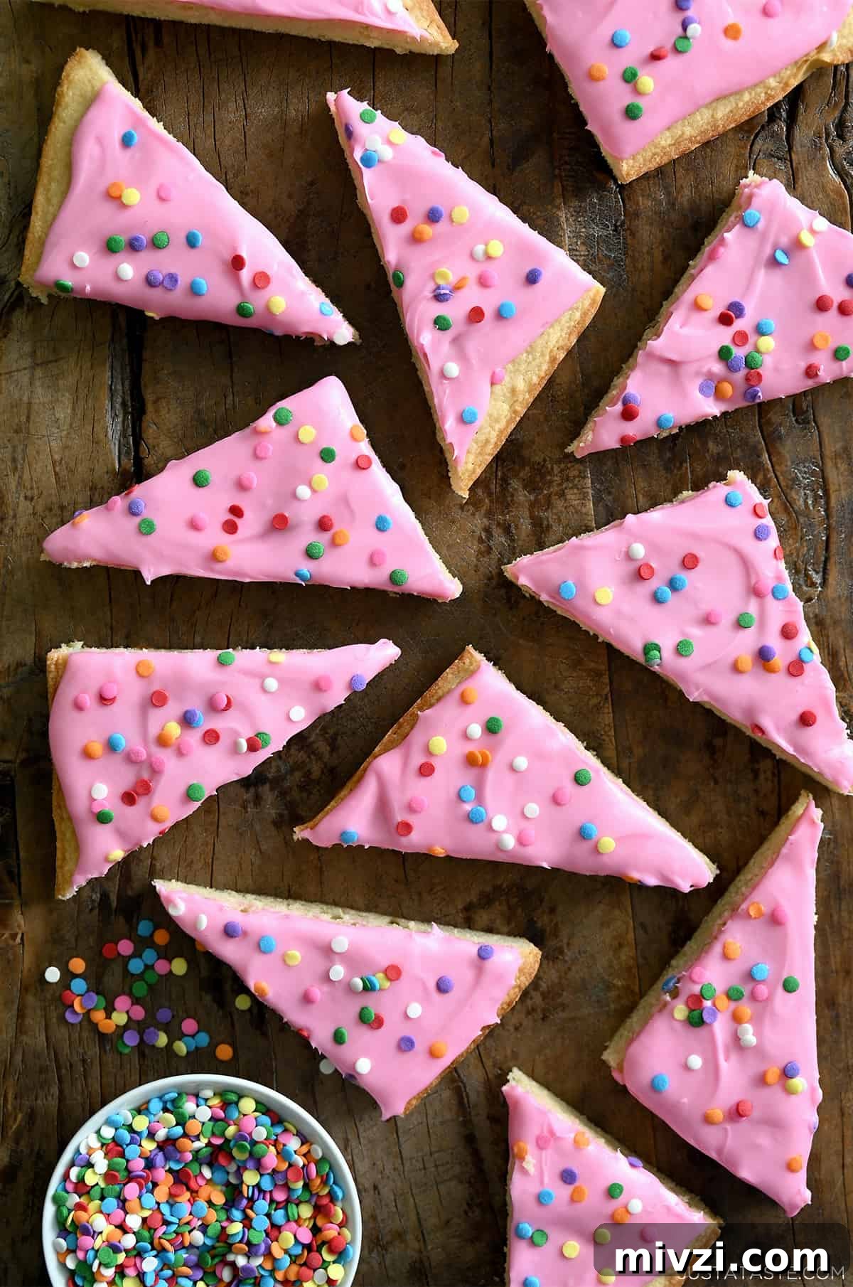 Romantic Valentine’s Day Dessert Ideas and Recipes 31 Pink-frosted sugar cookie bars with rainbow sprinkles next to a small bowl containing sprinkles.
