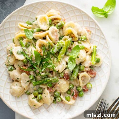 Top view of a plate with asparagus pasta with peas in creamy lemon pasta sauce.