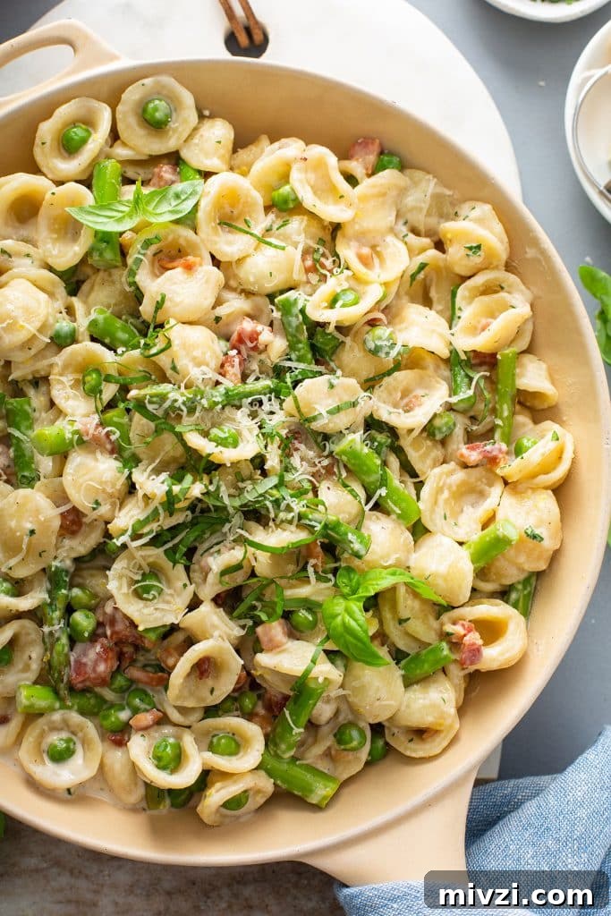 top view of a skillet with pasta with asparagus and bacon in a creamy lemon sauce