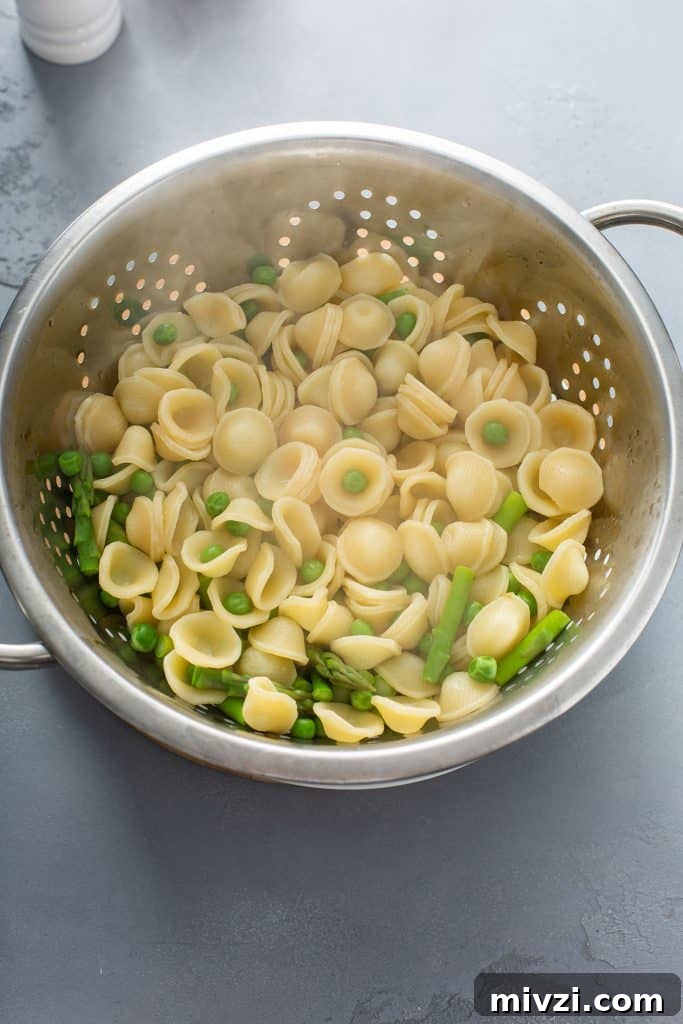 draining the pasta, asparagus and peas
