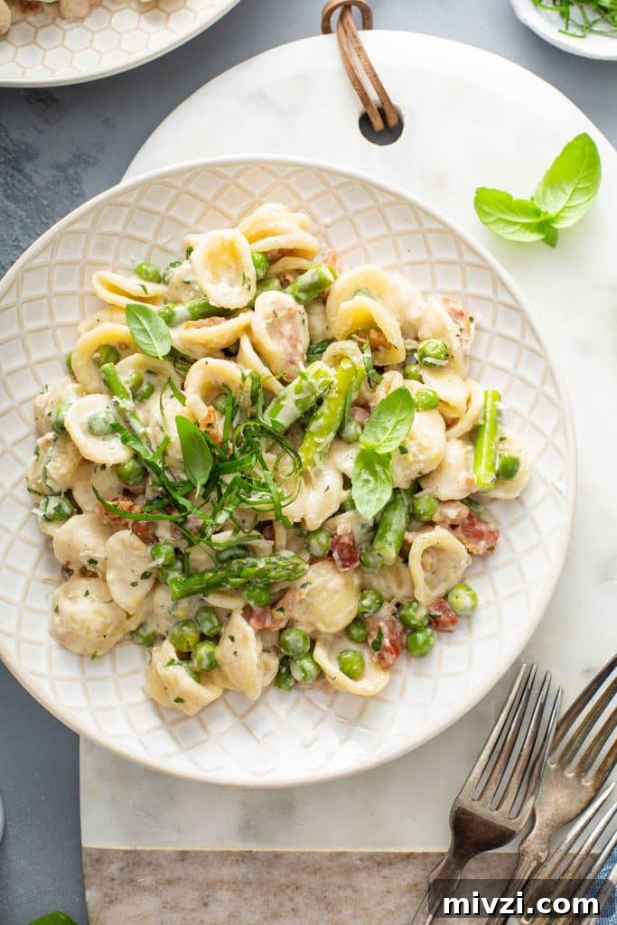 top view of a plate of creamy lemon pasta with asparagus, peas and pancetta.