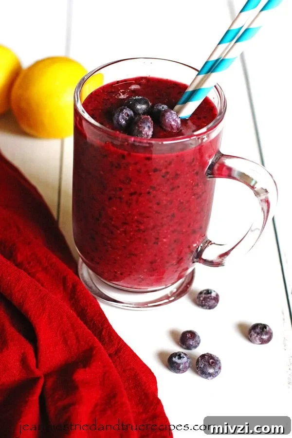 Refreshing Blueberry Lemon Smoothie Recipe for Morning Energy 2 Smoothie made with blueberries and lemon in a clear mug sitting on a white table.