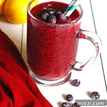 Refreshing Blueberry Lemon Smoothie Recipe for Morning Energy 7 Smoothie made with blueberries and lemon in a clear mug sitting on a white table.