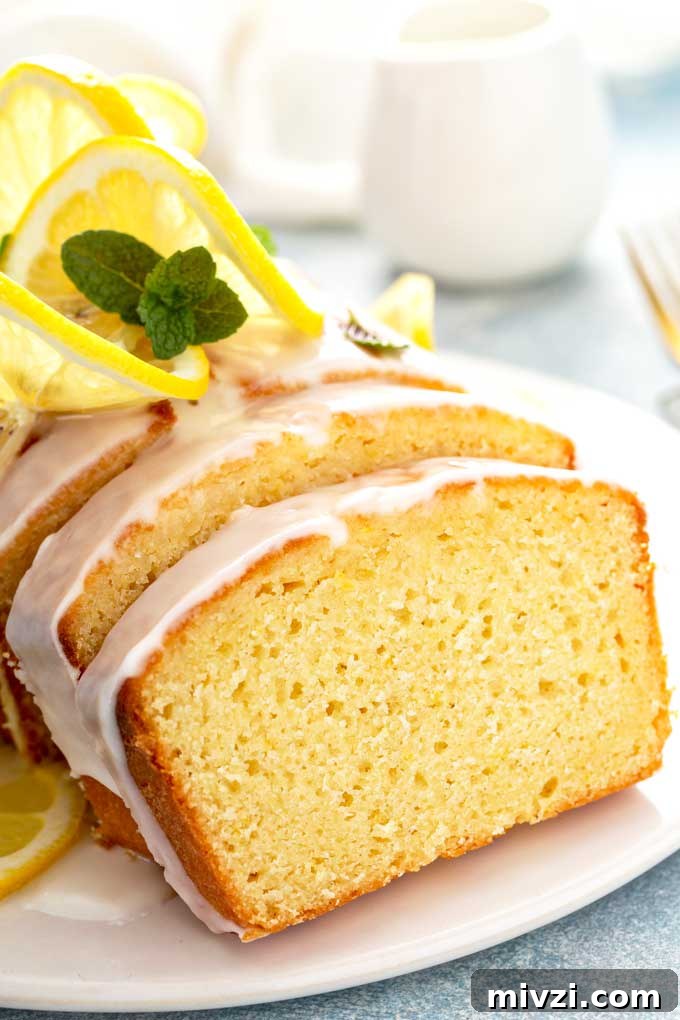 Tangy Lemon Loaf with Zesty Lemon Glaze 3 Close up view of a slice of lemon loaf on a white plate.