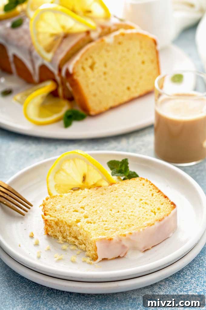 Tangy Lemon Loaf with Zesty Lemon Glaze 4 A slice of lemon bread with glaze on a white plate.