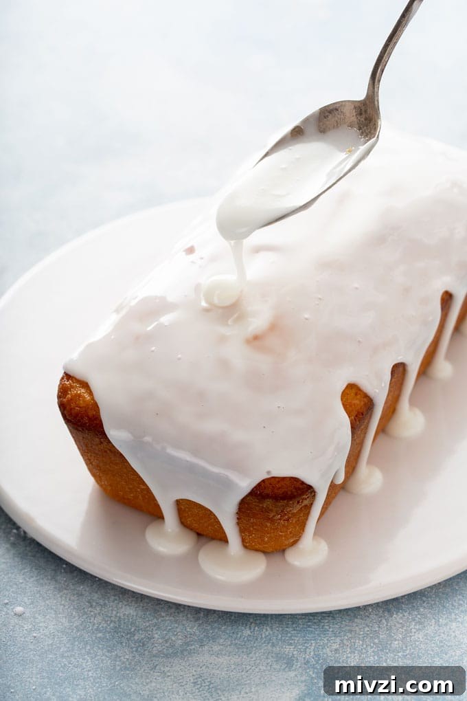 Tangy Lemon Loaf with Zesty Lemon Glaze 7 Lemon glaze getting poured over loaf cake.