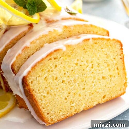 Tangy Lemon Loaf with Zesty Lemon Glaze 8 Close up slice of lemon pound cake with lemon glaze on a white plate.