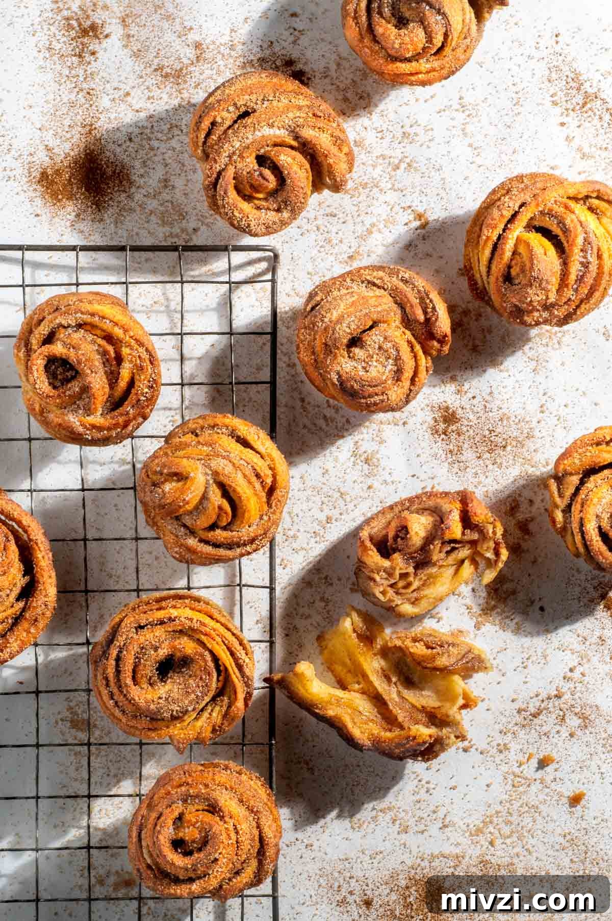 Canned Crescent Dough Cruffins Recipe: Flaky Homemade Pastry in Minutes 2 Cruffins scattered on a white background sprinkled with cinnamon sugar.