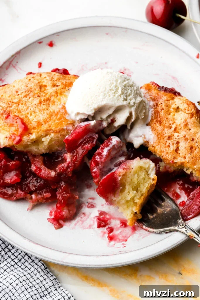 close up of cherry cobbler on a plate with ice cream